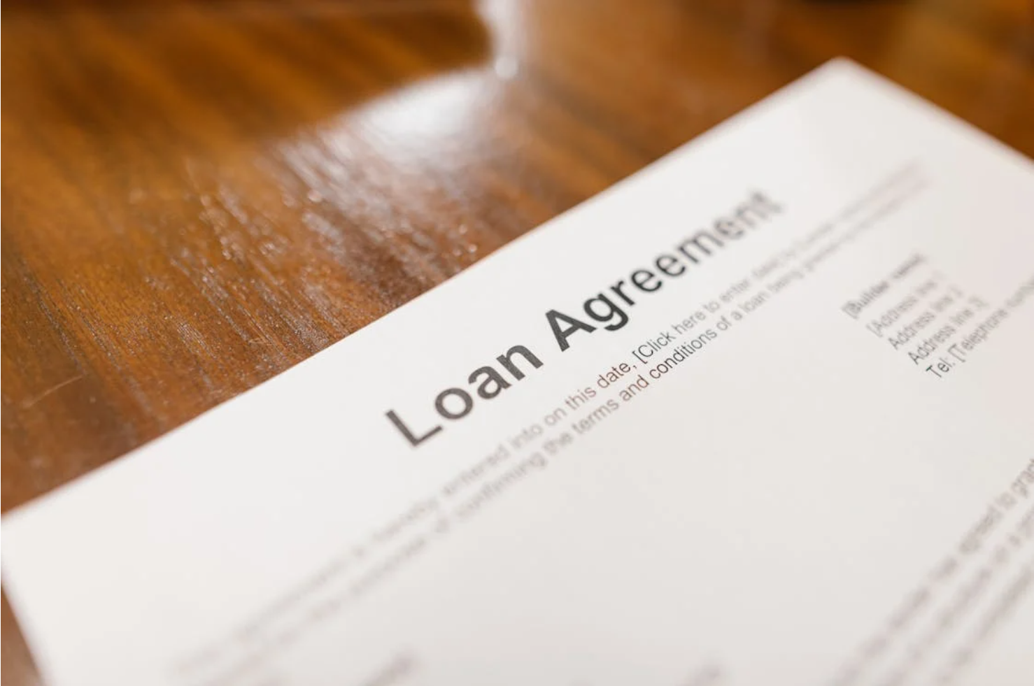 Document titled "Loan Agreement" placed on a flat surface, representing formal financial terms or lending contracts.